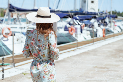 Seen from behind stylish woman in floral dress on pier