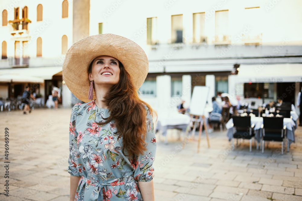happy modern woman in floral dress with hat enjoying promenade