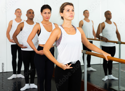 Ballet dancers perform exercises on a choreographic machine or barre on the background of a ballet class