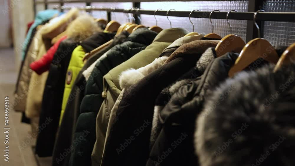 Many human jackets hang on hangers, empty hangers in foreground. Wardrobe. Refugee concert. The war in Ukraine. Russia attacked Many human jackets hang on hangers, empty hangers in foreground. Wardrobe. Refugee concert. The war in Ukraine. Russia attacked