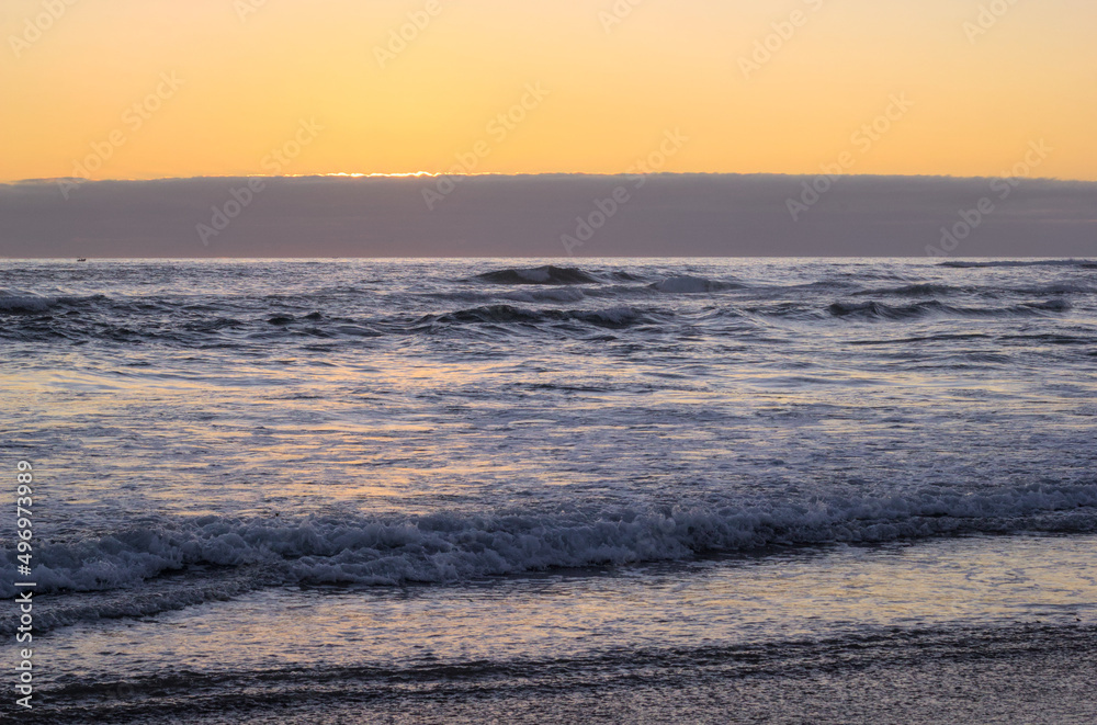 Obraz premium puesta de sol y ocaso en la orilla de playa con nubes en el horizonte y un pequeño bote