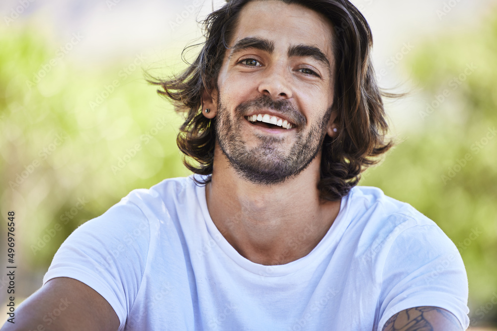 Take some time out for yourself. Shot of a young man sitting and smiling outside in the park. Take some time out for yourself. Shot of a young man sitting and smiling outside in the park.