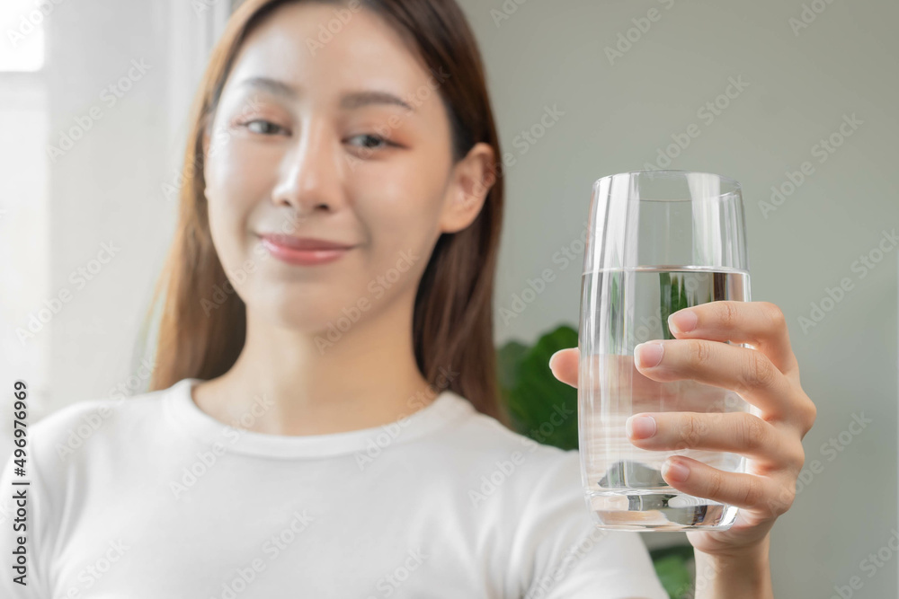 Happy beautiful, asian young woman, girl drinking, sip fresh glass of water for hydration of body, holding transparent glass in her hand, thirsty at home. Health care, healthy lifestyle concept. Happy beautiful, asian young woman, girl drinking, sip fresh glass of water for hydration of body, holding transparent glass in her hand, thirsty at home. Health care, healthy lifestyle concept.