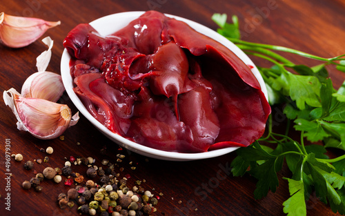 Fresh rabbit liver with condiments on wooden table