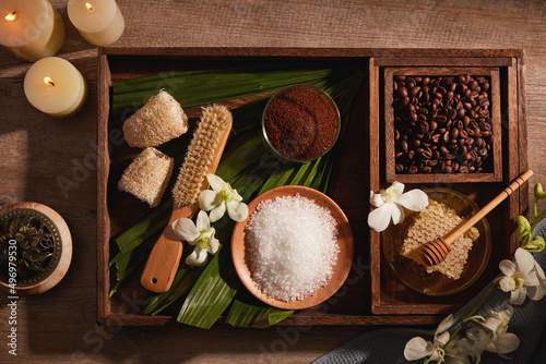 A closeup view of coffee bean and powder decorated with wooden tray candles and flower in wooden background for exfoliating advertising , mixture of coffee and salt  photo