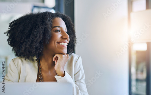 There are so many possibilities to look forward to. Shot of a young businesswoman smiling and looking out of a window in her office.