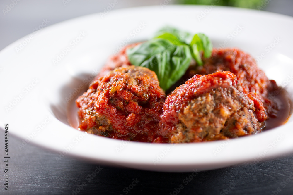 A closeup view of a plate of meatballs in marinara sauce. A closeup view of a plate of meatballs in marinara sauce.