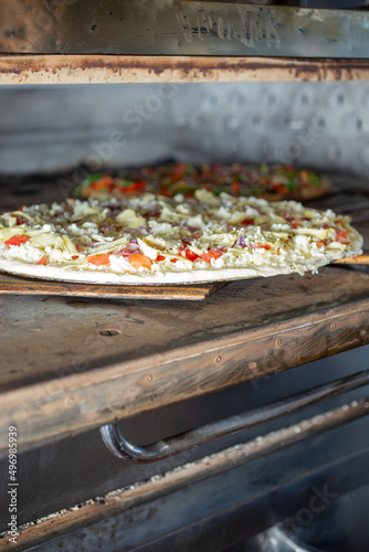 A view of a pizza baking inside a commercial grade pizza oven, seen at a local restaurant.
