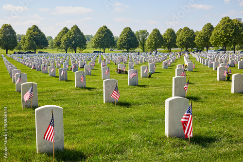 Graveyard of fallen soldiers with American flags on all of the white grave stones