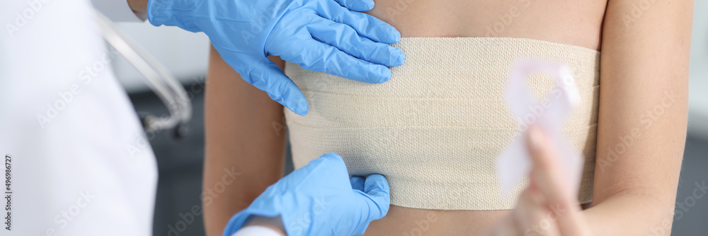 Fototapeta premium Doctor mammologist examining breast of female patient with elastic bandage closeup