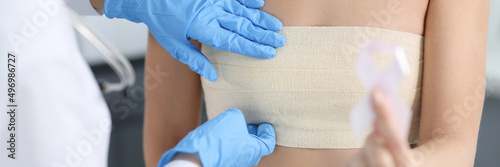 Tableau sur toile Doctor mammologist examining breast of female patient with elastic bandage close