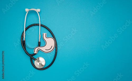 A stethoscope and stomach shape made from paper are over a blue background