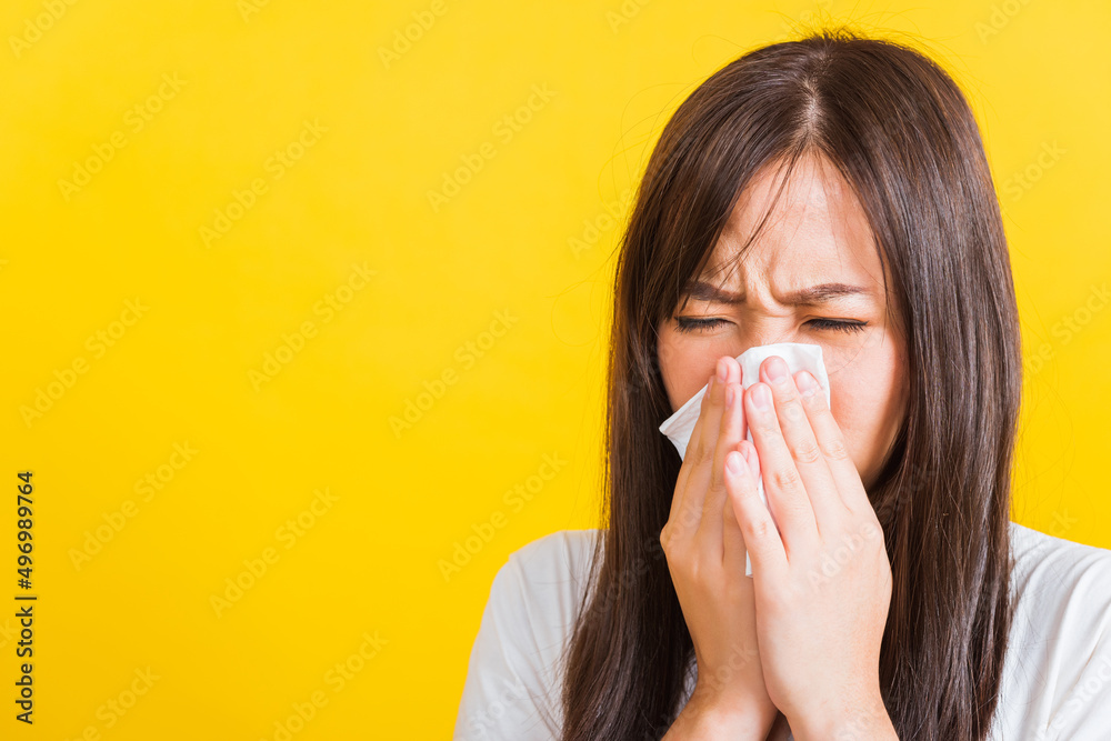 Portrait of Asian beautiful young woman sad she crying wipe the mucus with tissue, Close up of pretty girl sneezing sinus using towel to wipe snot from nose, studio shot isolated on yellow background