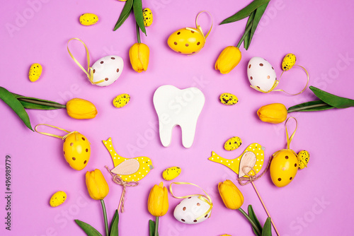 White tooth with Easter decorations on purple background. Dentist Easter concept.