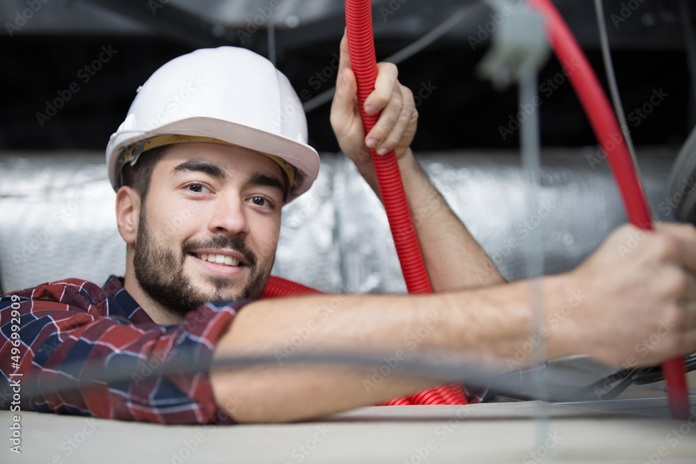 contractor in roof space installing red cable conduit contractor in roof space installing red cable conduit