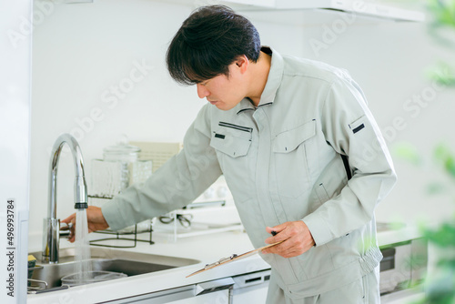 Foto キッチンと作業着姿の男性（水道）