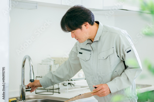 キッチンと作業着姿の男性（水道） 