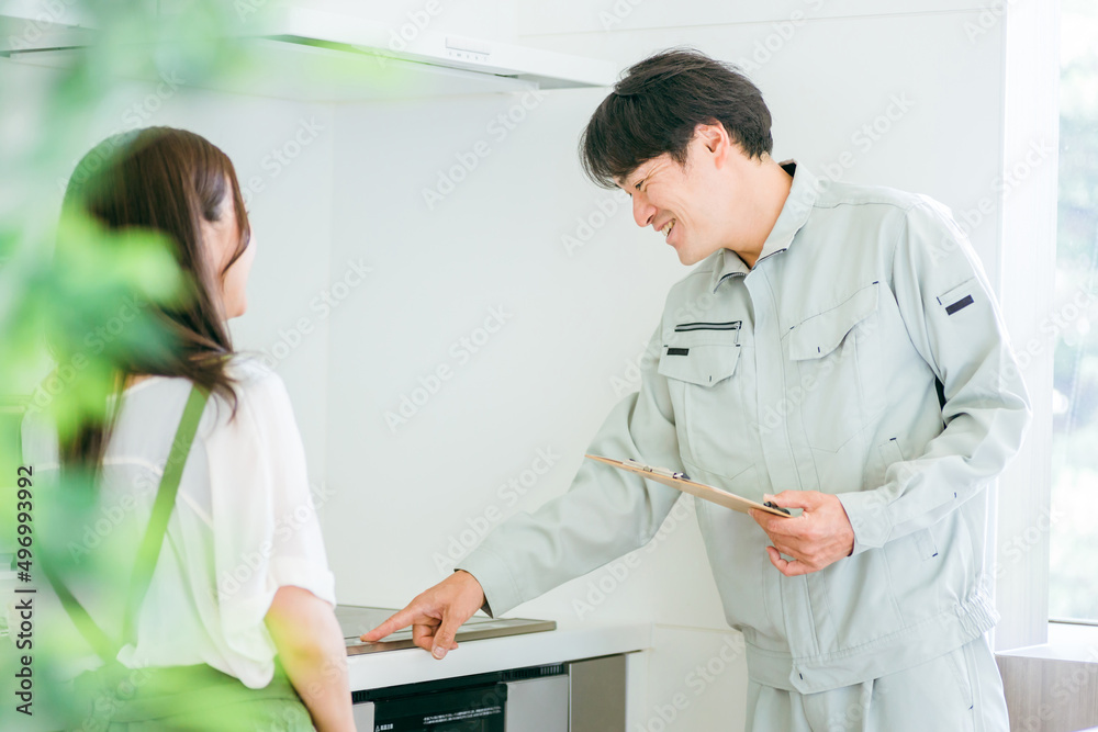 Fototapeta premium キッチンで話す作業着姿の男性と女性(IH・笑顔)