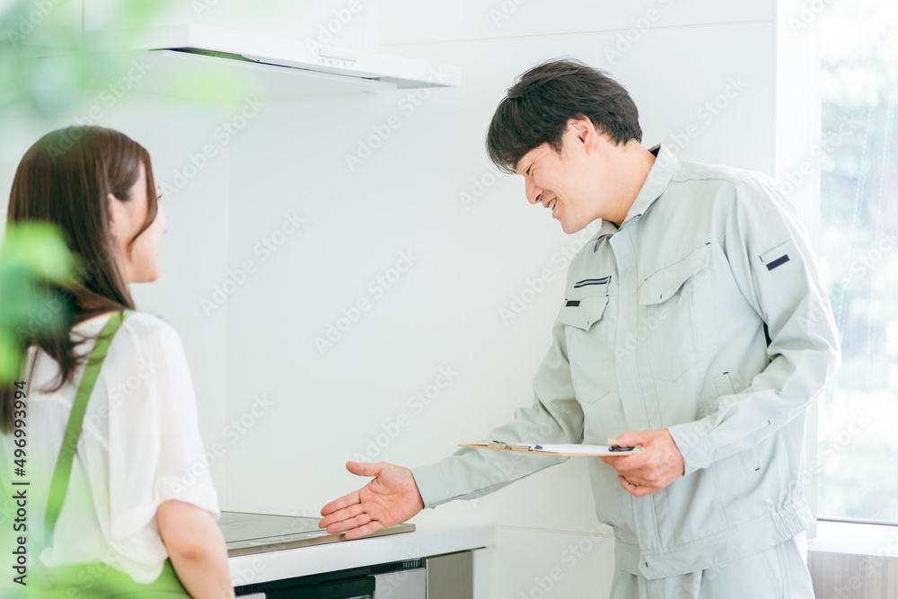 Obraz premium キッチンで話す作業着姿の男性と女性（IH・笑顔） 