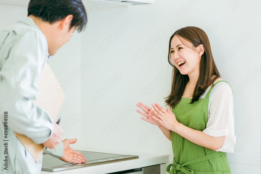 Fototapeta premium キッチンで話す作業着姿の男性と女性（食洗機） 