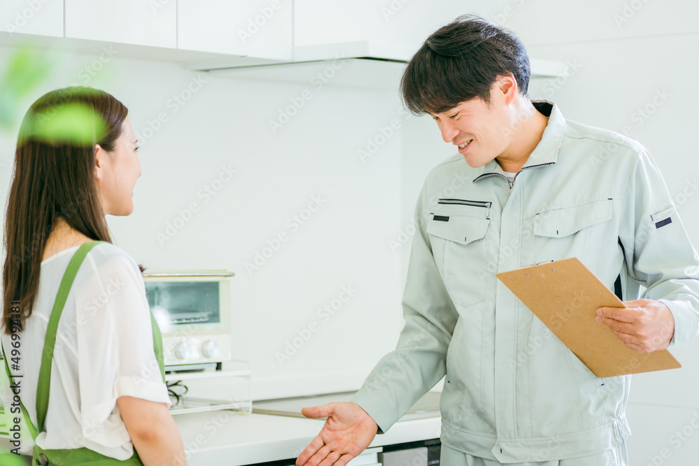 Obraz premium キッチンで話す作業着姿の男性と女性(食洗機)