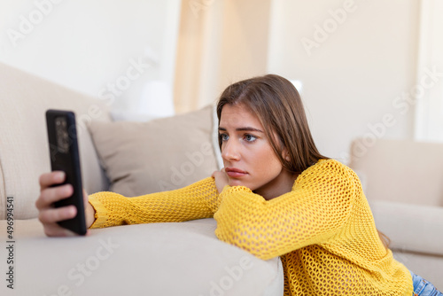 Fotobehang Pensive sad young woman holding smartphone waiting sms from boyfriend