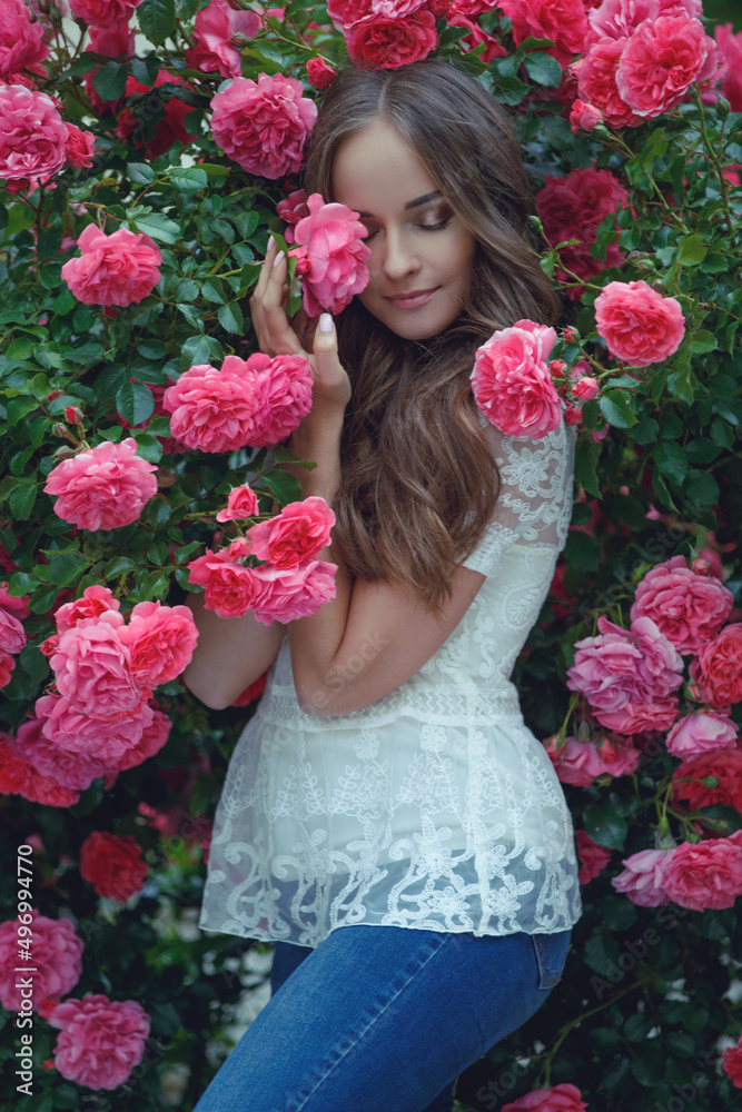 Beautiful portrait of a woman in poses. A brunette woman is standing next to roses in nature. Beautiful portrait of a woman in poses. A brunette woman is standing next to roses in nature.