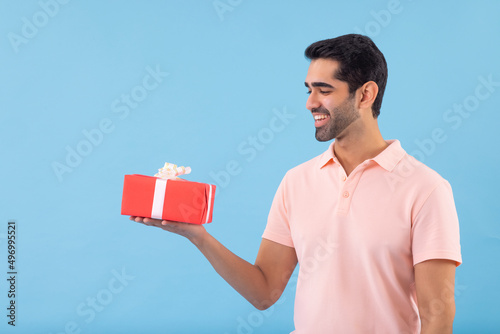 Portrait of cheerful young man holding gift in hand