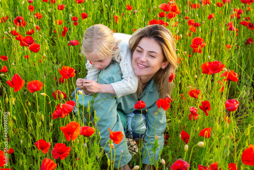 Mom with a child girl in a field of red poppies enjoys nature. Mother and little daughter in the poppy field. Mother and daughter on spring. © Volodymyr