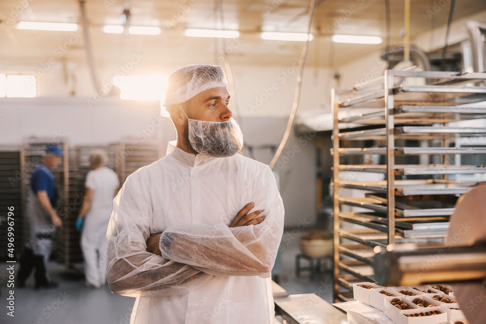 A proud food factory worker with arms crossed standing at the factory. A proud food factory worker with arms crossed standing at the factory.