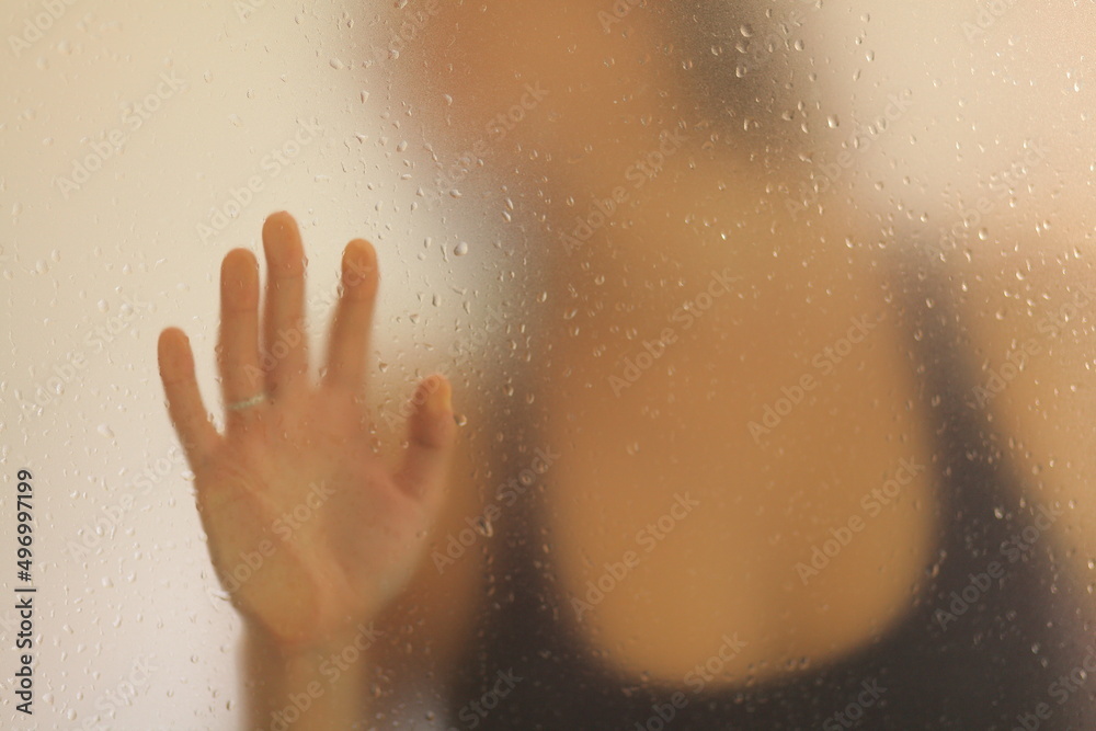 View of an unrecognizable woman placing her hand behind a frosted glass