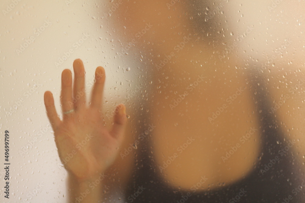 View of an unrecognizable woman placing her hand behind a frosted glass View of an unrecognizable woman placing her hand behind a frosted glass