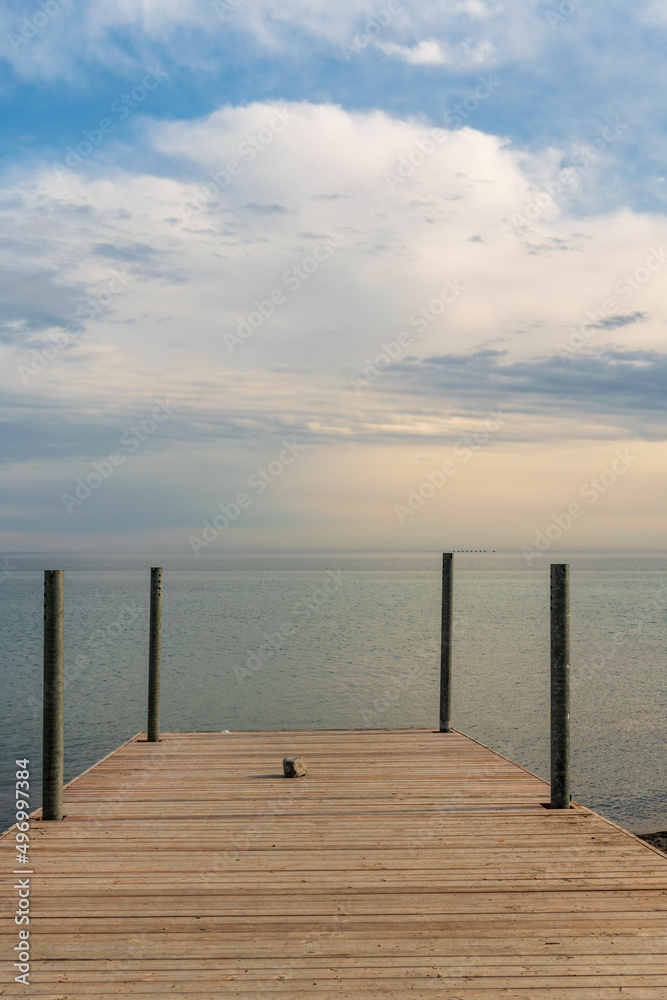 Obraz premium Looking out to the horizon from a simple wooden dock. Shot in Toronto's iconic Beaches neighbourhood in early spring. Room for text.