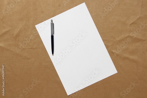 Template of white paper with pen lies diagonally on light brown cloth background. Concept of business plan and strategy. Stock photo with empty space for text and design. © Stanislav