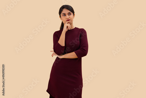 Portrait of a young woman looking elsewhere and thinking with hand on chin