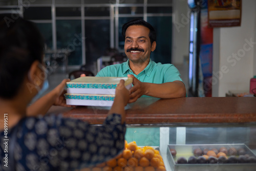 Sweet shop owner selling sweet to customer