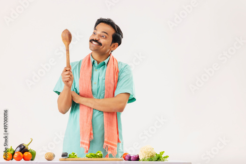 Cook servant looking at wooden spatula holding in hand