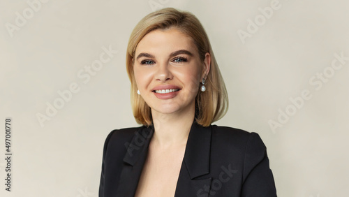 Portrait of an elegantly dressed young Caucasian business woman on a beige background. Blond female with trendy short haircut