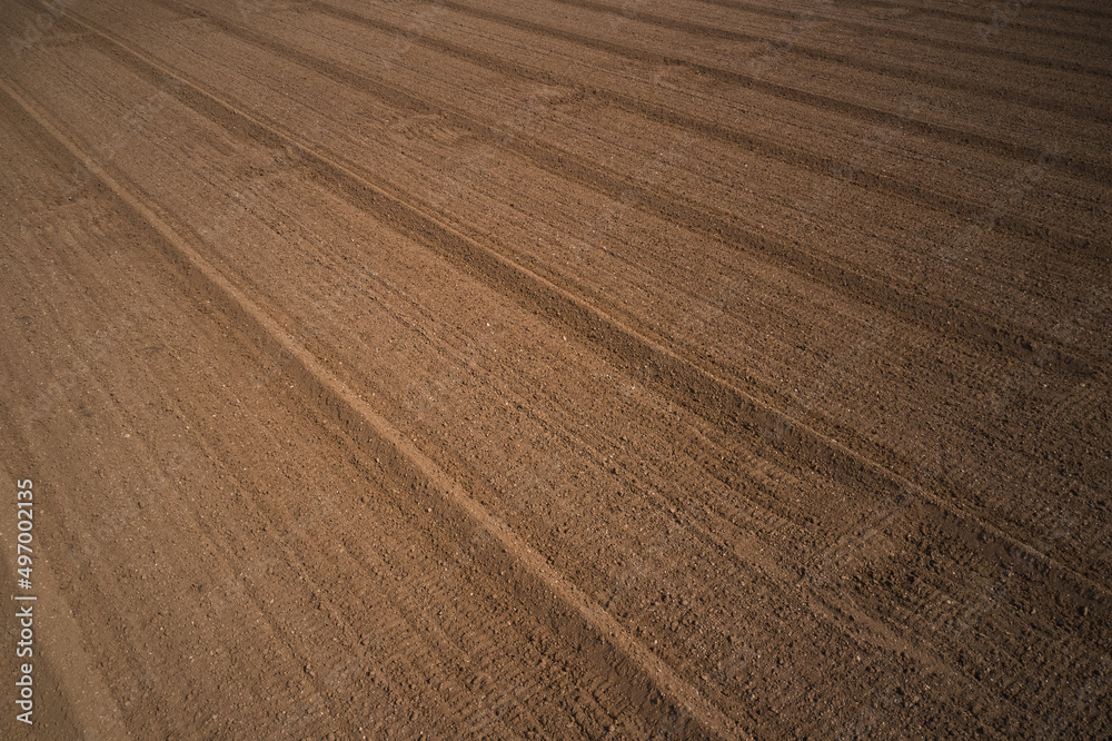 Background of brown earth at high altitude aerial view. Aerial drone view of freshly plowed field ready for seeding and planting in spring. Plowed field in Italy, drone view.