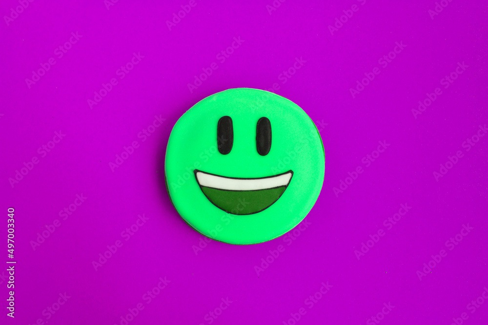 Green smiley in the form of gingerbread on the purple background. Closeup. Copy space. Green smiley in the form of gingerbread on the purple background. Closeup. Copy space.