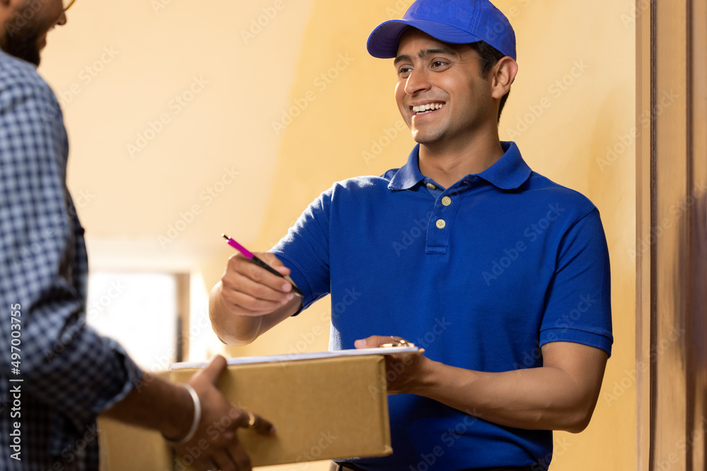 Young delivery boy requesting customer to sign receipt after receiving parcel Young delivery boy requesting customer to sign receipt after receiving parcel