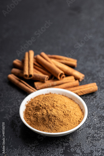 Dry cinnamon sticks and cinnamon powder on black table. Cinnamon spice.