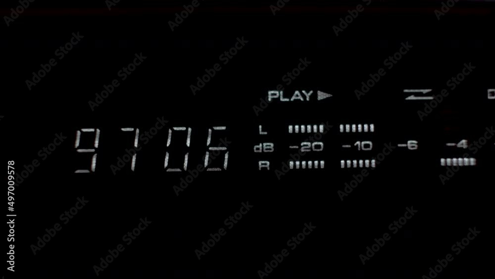 A close up shot of a digital display unit of a tape deck stereo system, the display providing a time metre and decibel reading as music is played from an old cassette