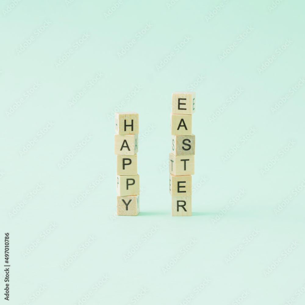 The inscription Happy Easter on wooden cubes on a pastel green background. Minimal concept. The inscription Happy Easter on wooden cubes on a pastel green background. Minimal concept.