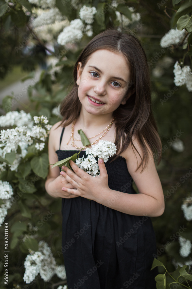 little girl with lilac walks in the park