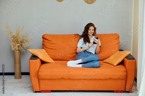 cheerful woman with a phone in his hands on the couch apartments