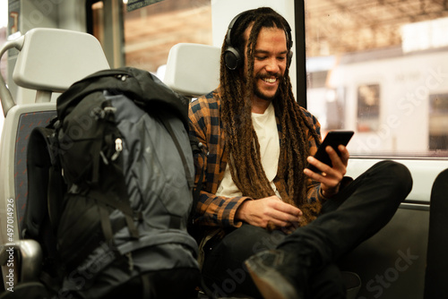 Young man listening the music while traveling by a train. Handsome young man traveling by a train...