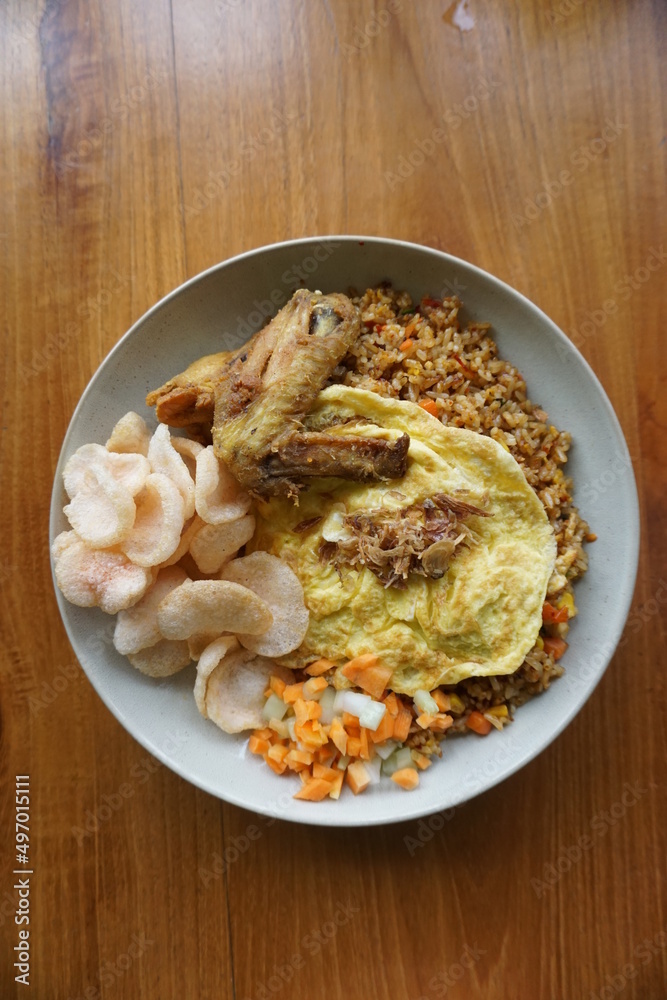 proper breakfast menu. a plate of fried rice topped with fried chicken, omelette and crackers.