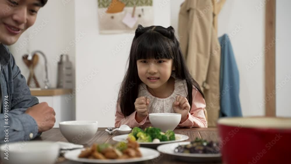 selective focus of hungry Asian girl saying wow with admiration her mom is serving tasty food on dining table. she picks up her chopsticks getting ready to eat selective focus of hungry Asian girl saying wow with admiration her mom is serving tasty food on dining table. she picks up her chopsticks getting ready to eat