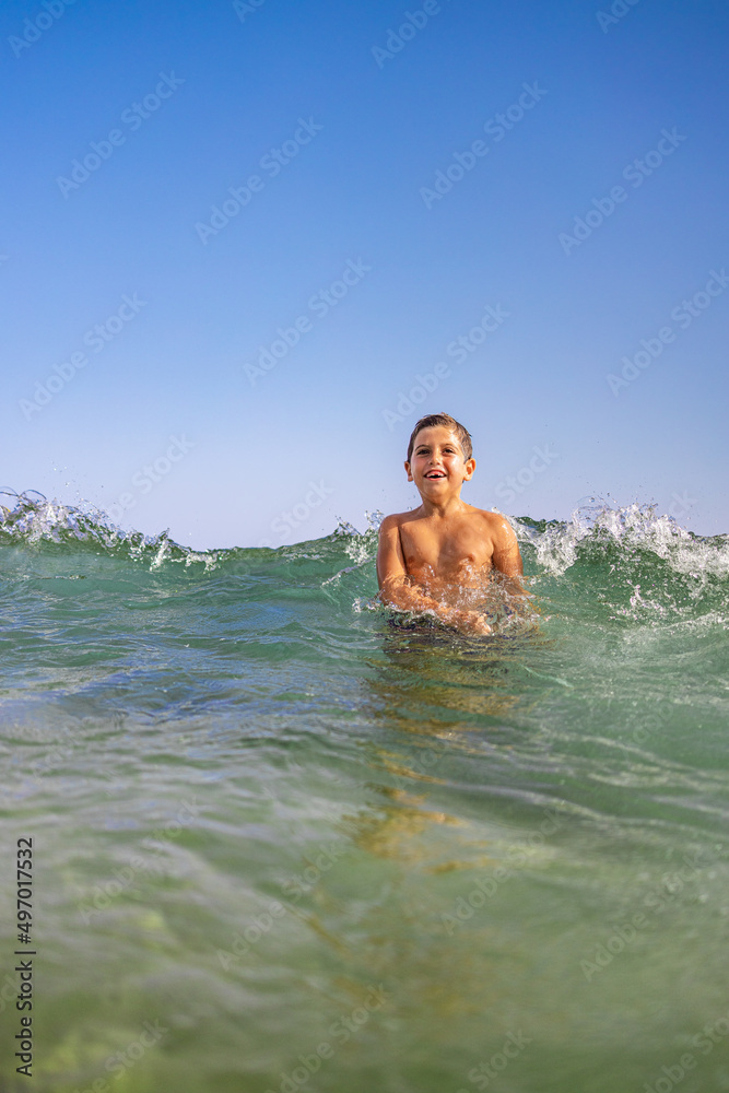 Funny kid playing with waves on the beach